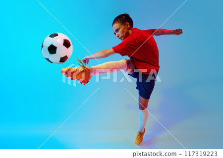 Dynamic photo of female soccer player in action kicks ball in neon light against colorful gradient background. Dynamic photo of female soccer player in action kicks ball in neon light against colorful gradient background. 117319223