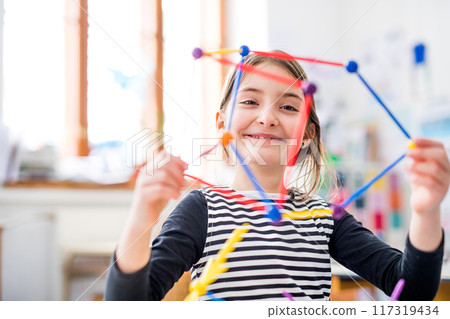 Portrait of schoolgirl using educational tool, learning geometry during class, feeling accomplished. Student girl in classroom at the elementary school 117319434