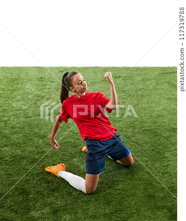 Female football player kneeling on green grass at stadium in triumphant pose and clenching fists, shouting of joy. Score winning goal in final game. Female football player kneeling on green grass at stadium in triumphant pose and clenching fists, shouting of joy. Score winning goal in final game. 117319788
