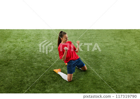 Female football player kneeling on green grass at stadium in triumphant pose and clenching fists, shouting of joy. Score winning goal in final game. Female football player kneeling on green grass at stadium in triumphant pose and clenching fists, shouting of joy. Score winning goal in final game. 117319790