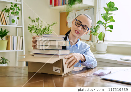 Woman with new books unpacked from cardboard box 117319889
