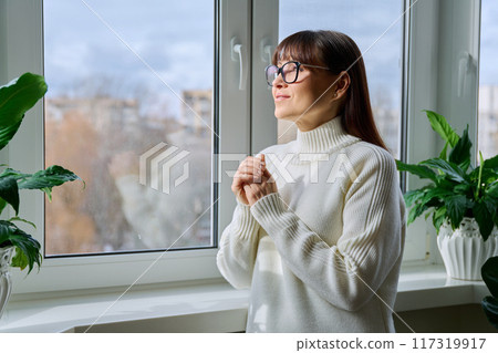 Beautiful happy middle aged woman looking out the window Beautiful happy middle aged woman looking out the window 117319917
