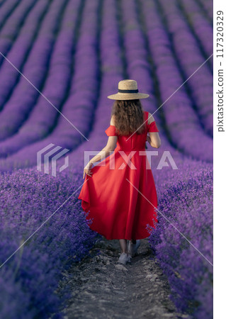 A woman in a red dress is walking through a field of purple flowers A woman in a red dress is walking through a field of purple flowers 117320329