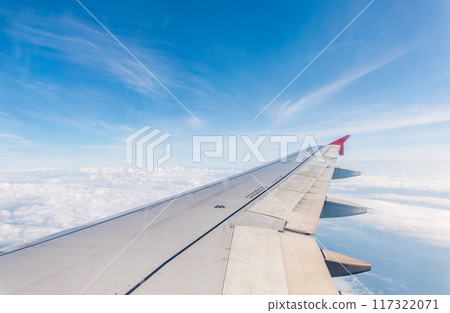View from the airplane window at a beautiful cloudy sky and the airplane wing View from the airplane window at a beautiful cloudy sky and the airplane wing 117322071