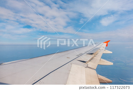 View from the airplane window at a beautiful cloudy sky and the airplane wing View from the airplane window at a beautiful cloudy sky and the airplane wing 117322073