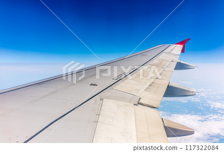 View from the airplane window at a beautiful cloudy sky and the airplane wing View from the airplane window at a beautiful cloudy sky and the airplane wing 117322084