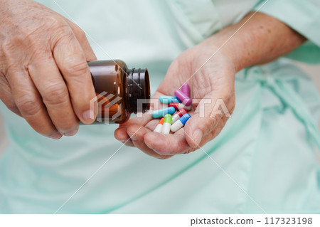 Asian elderly woman holding pill drug in hand, strong healthy medical concept. 117323198