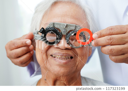 Optometrist checking Asian elderly woman ophthalmic vision eye test and using optical trial frame. 117323199
