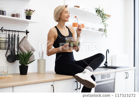 Woman enjoying healthy salad in modern kitchen 117323272