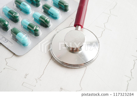 Stethoscope on electrocardiogram ECG with capsule drug, heart wave, heart attack, cardiogram report. 117323284