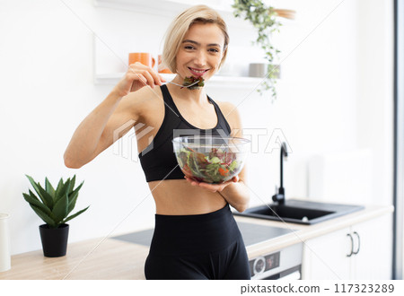 Woman enjoying healthy salad in modern kitchen Woman enjoying healthy salad in modern kitchen 117323289