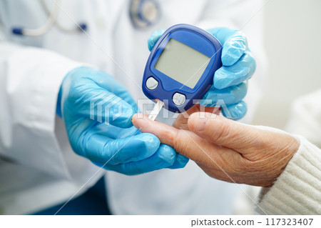Asian doctor using digital glucose meter for check sample blood sugar level to treatment diabetes. Asian doctor using digital glucose meter for check sample blood sugar level to treatment diabetes. 117323407