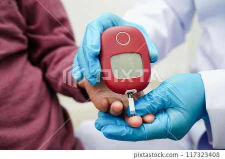 Asian doctor using digital glucose meter for check sample blood sugar level to treatment diabetes. Asian doctor using digital glucose meter for check sample blood sugar level to treatment diabetes. 117323408