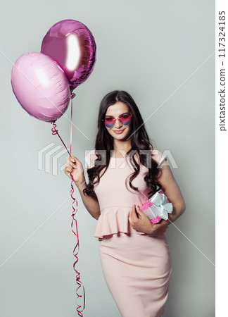 Nice brunette woman holding helium balloon and birthday present gift. Happy model  117324185
