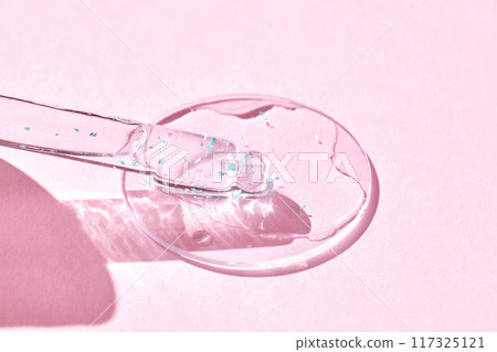 Serum gel texture swatch. Transparent drop with golden sparkles. Pink background Serum gel texture swatch. Transparent drop with golden sparkles. Pink background 117325121