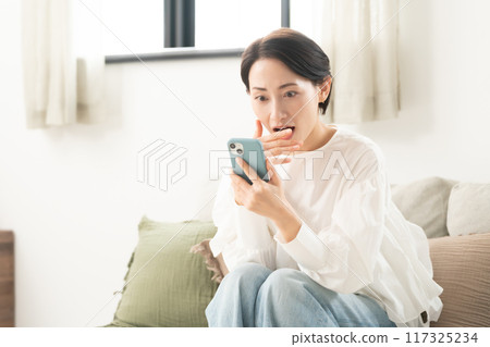 一個女人驚訝地看到一部智能手機 117325234