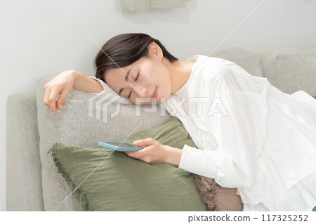 一個女人帶著智慧型手機睡覺 117325252