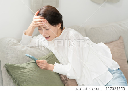 一位女士看著她的智慧型手機感嘆道 117325253