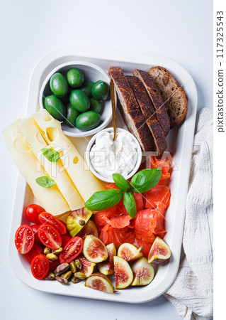 Salmon, cheese, olives and vegetables breakfast platter, white background. Salmon, cheese, olives and vegetables breakfast platter, white background. 117325543