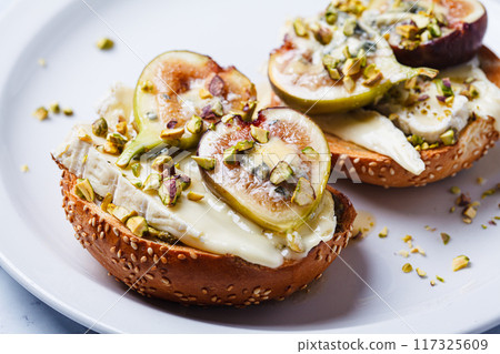 Toasts with pesto, brie, dorblu, fig and pistachio. 117325609