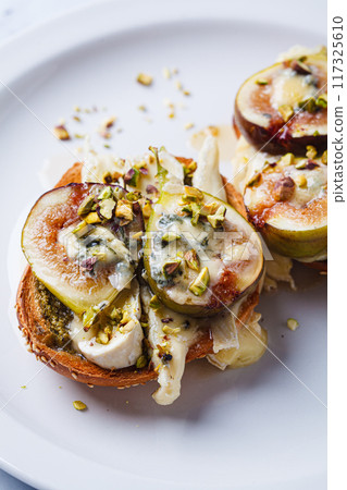Toasts with pesto, brie, dorblu, fig and pistachio. Toasts with pesto, brie, dorblu, fig and pistachio. 117325610