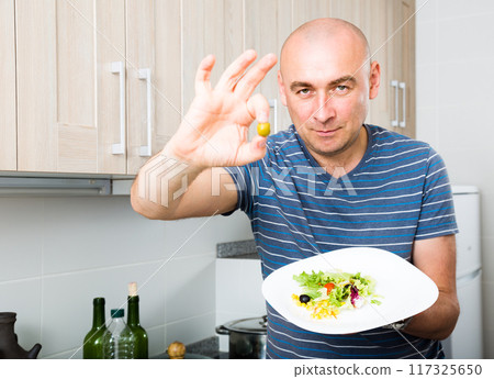 Man holding fingers in green olives Man holding fingers in green olives 117325650