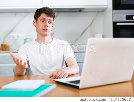 Young guy studying at home with laptop 117325667