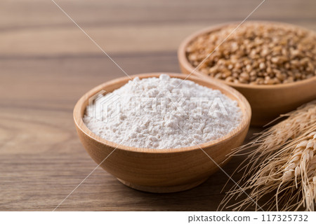 Wheat flour and wheat grain in bowl on wooden table, Food ingredient 117325732