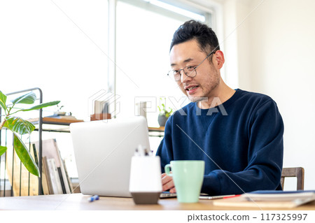A man looking at the screen while working on a computer with an awkward, slightly surprised expression A man looking at the screen while working on a computer with an awkward, slightly surprised expression 117325997