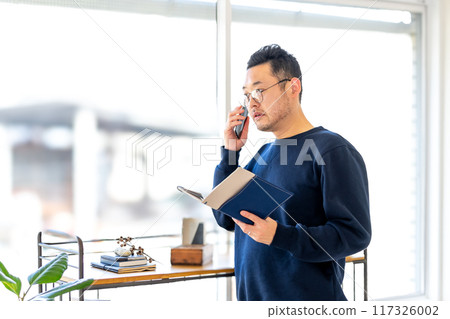 一名男子使用手持筆記型電腦的智慧型手機接聽電話 117326002