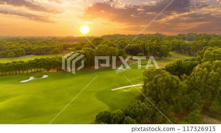 Golf course at sunset. Scenic panoramic aerial view of golf course at sunset with beautiful sky. Drone view Golf course at sunset. Scenic panoramic aerial view of golf course at sunset with beautiful sky. Drone view 117326915