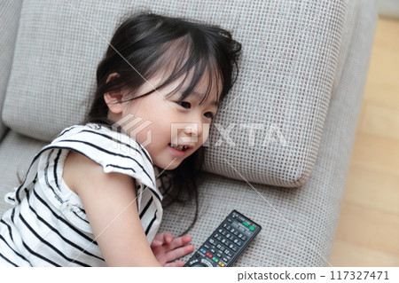 3 歲女孩躺在沙發上放鬆看電視 117327471