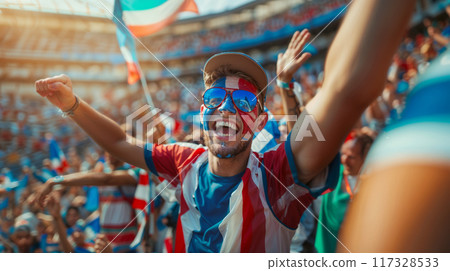 Young male sports fan with painted face is cheering on his team at a crowded stadium 117328533