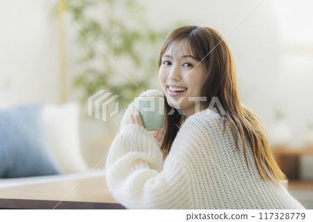 A young woman in knitwear relaxing in a room 117328779