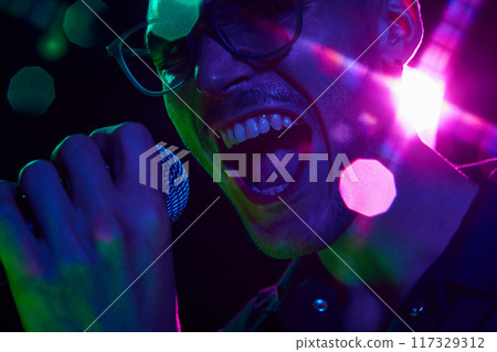 Vibrant neon hues highlight the intensity of vocalist in heat of performance, his powerful voice visible in every detail. 117329312