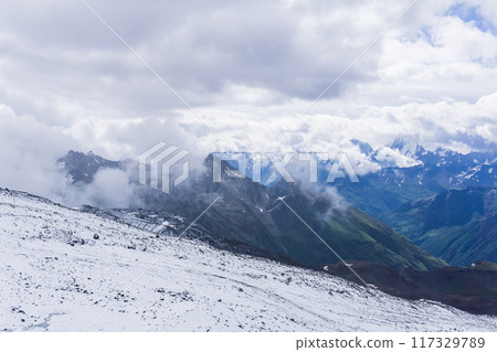 mountain landscape, view from high mountain snow slope to cloud covered valleys 117329789