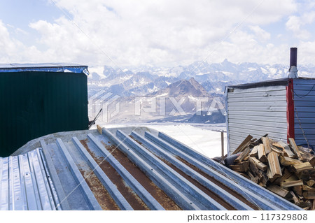 view of snowy peaks through roofs of mountain huts in highlands 117329808