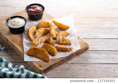 Fried potato wedges wooden table. Copy space 117330301