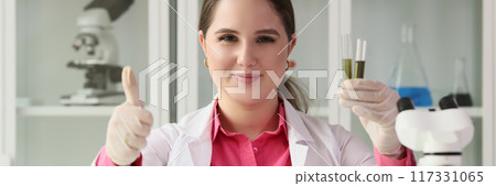 Woman chemist holding test tubes and showing thumbs up sign Woman chemist holding test tubes and showing thumbs up sign 117331065