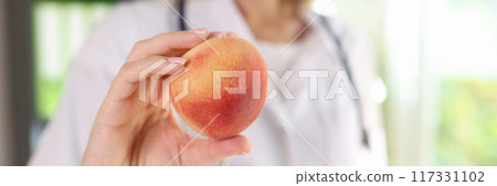 Doctor nutritionist holding ripe peach in hand 117331102