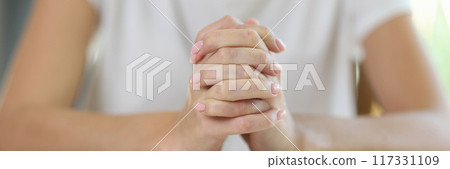 Woman sitting at table and putting hands in lock on book 117331109
