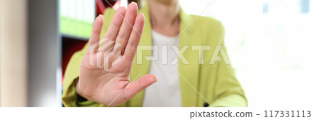 Female sitting in office and showing stop sign or protesting gesture 117331113