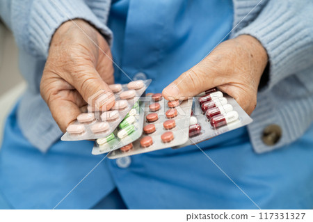 Asian senior woman patient holding antibiotics capsule pills  for treatment infection patient in hospital, Pharmacy drugstore concept. 117331327