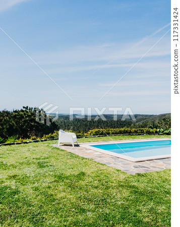 A serene poolside setting with white lounge chairs overlooking a panoramic view A serene poolside setting with white lounge chairs overlooking a panoramic view 117331424