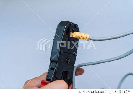 Specialist crimps connector on network cable using crimper 117331549