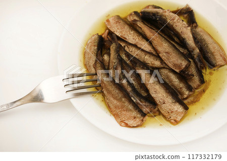 Sprats on a white plate with a fork. Canned fish in oil. Fish appetizer. Sprats on a white plate with a fork. Canned fish in oil. Fish appetizer. 117332179