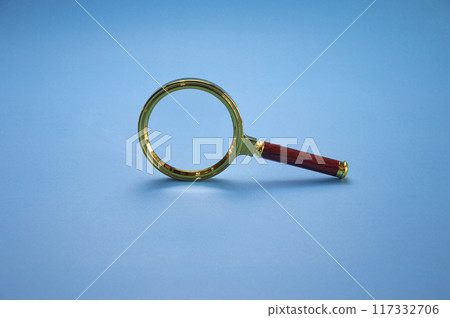 Magnifying glass with colored frame The handle is made of wood on a blue background. Magnifying glass with colored frame The handle is made of wood on a blue background. 117332706