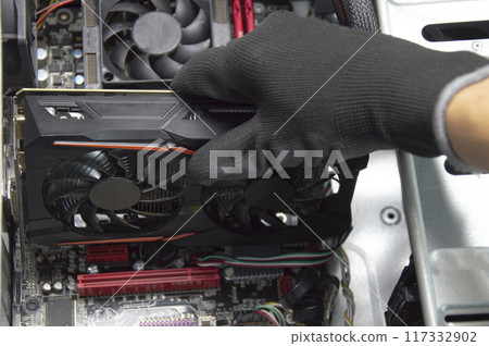 Top view of graphics card being assembled by technician on motherboard, computer repair 117332902