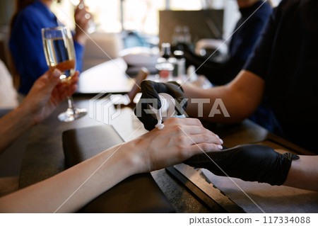 Manicurist applying cream on client hand in luxury beauty salon 117334088