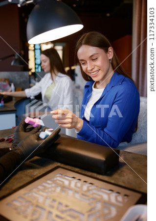 Professional manicurist offering colorful nail polish flask to client closeup Professional manicurist offering colorful nail polish flask to client closeup 117334103
